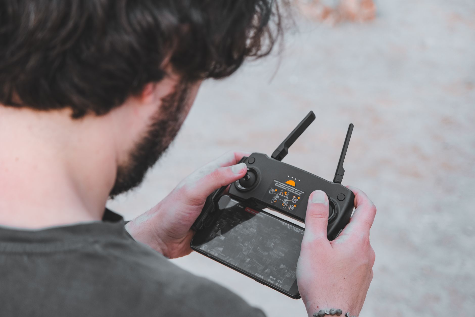 Drone operator using remote controller outdoors, relevant to UK drone regulation compliance